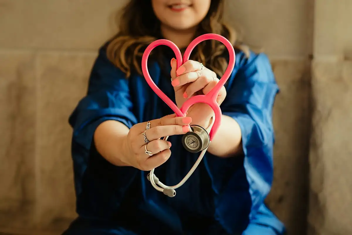 Hands holding a stethoscope shaped like a heart